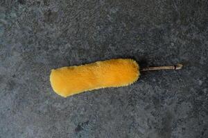 Yellow duster on a grey concrete surface. photo