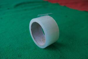 A roll of transparent tape on a green surface. photo