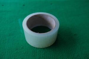Roll of transparent tape on a green surface. photo