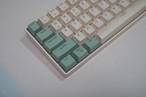 Close-up of a white keyboard with teal keys. photo