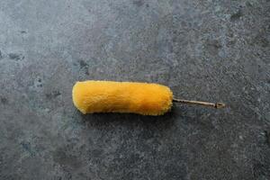 Yellow fluffy duster on a gray textured surface. photo