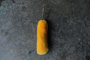 Yellow duster on a grey concrete surface. photo