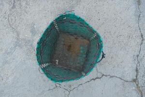 Top view of an empty green woven basket on a cracked concrete surface. photo