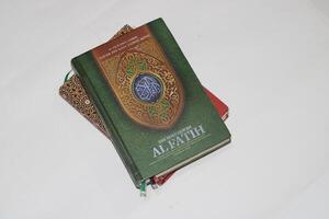 Close up of a green Quran with ornate details on a white background. photo