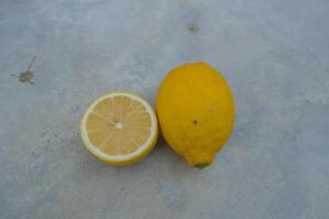 A whole lemon and a lemon half on a gray surface. photo