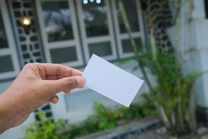 Hand holding blank card against blurred background. photo