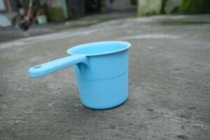 Blue plastic dipper on a concrete surface. photo