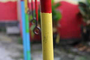Close-up of a yellow and red painted pole with a metal ring. photo