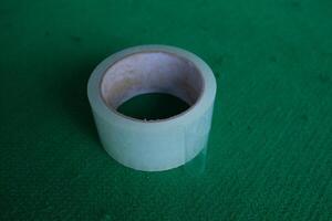 A roll of clear packing tape on a green surface. photo