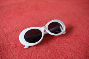 White sunglasses on red textured background. photo
