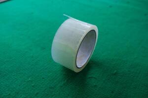 Clear adhesive tape roll on green background. photo