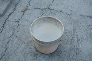 Empty white bucket on a cracked concrete surface. photo