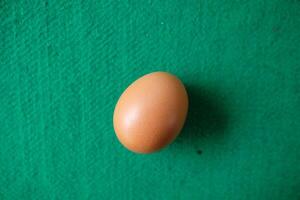 One brown egg on a green surface. photo