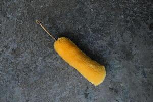 Yellow duster on a gray textured surface. photo