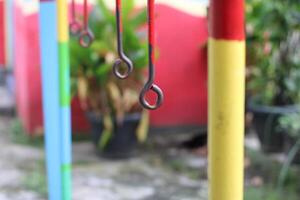 Close-up of a rusty metal ring hanging from a colorful pole. photo