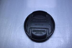 Black lens cap with 58mm size on a textured white background. photo