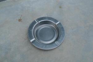 Empty metal ashtray on a concrete surface. photo