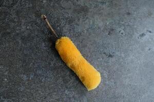 Yellow duster on a grey concrete surface. photo