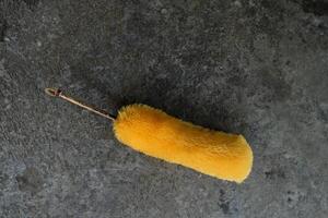 Yellow duster on a gray textured surface. photo