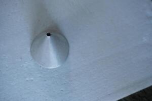 Close-up of a metal cone on a white surface. photo