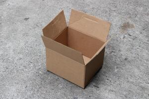 Empty cardboard box open on gray concrete floor. photo