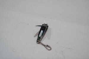 A close-up of a silver nail clipper with a chain. photo