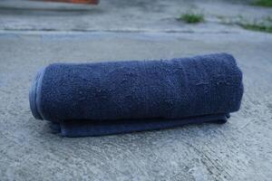 Rolled up dark blue towel on a concrete surface. photo
