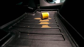 Pollution of the car in the cabin. a woman's hand drops a disposable paper cup onto the car floor mat. Spilled coffee on the carpet in the car. video