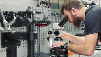 Diagnostics of diesel injectors under a microscope. The master examines the nozzle under a microscope to detect defects. video