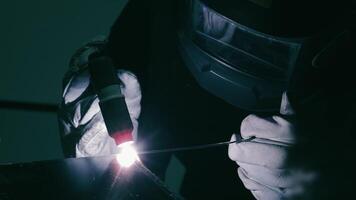 Focused welding with protective helmet. A close-up of a welder wearing a protective helmet, carefully working on a metal surface. video