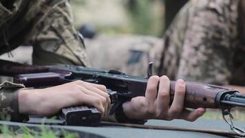 Soldier preparing rifle during training in prone position. A close-up of a soldier preparing an assault rifle while lying prone during a training exercise. video