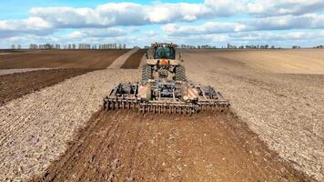 Rear view of a tractor plowing a field with a plow. Processing of agricultural lands. video