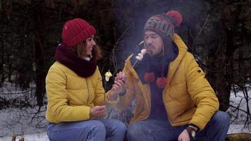 Young man and woman on a picnic in the winter forest. Tourists travel together. The guys are smiling and chatting. Travel and adventure concept. close-up video