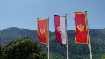 the flags of Montenegro and Kotor are fluttering in the wind against the background of the sky and mountains. High quality 4k footage video