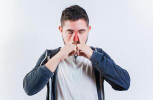 Suffering man with nasal congestion isolated. Sore person suffering with nasal bridge on isolated background photo