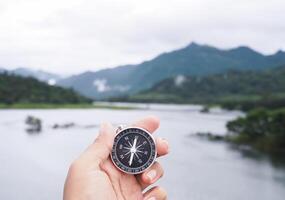 Close up of compass in woman hand with nature as background. The concept of world tourism day, Searching the right directions and Travel photo
