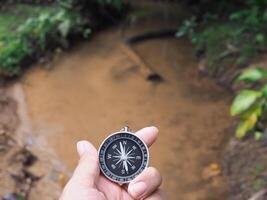 Close up of compass in woman hand with nature as background. The concept of world tourism day, Searching the right directions and Travel photo