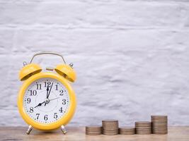 Yellow alarm clock and stack of coins. The concept of saving money and manage time to success business, Financial, Investment and Business growing up. photo