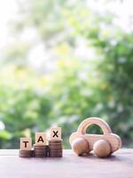 Wooden toy car and wooden blocks with the word TAX on stack of coins. The concept of saving and manage money to success transportation, Paying tax and car loan photo