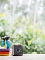 Student creative desktop, earth globe with graduation hat on hardcover book and 2025 desk calendar. Copy space for text, Back to school, Education concept photo