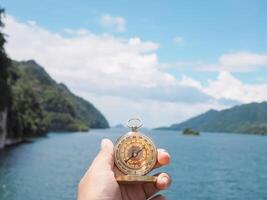 Close up of compass in woman hand with nature as background. The concept of world tourism day, Searching the right directions and Travel photo