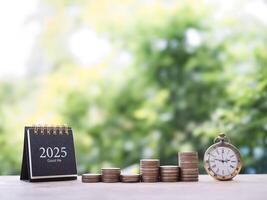 Vintage watch, 2025 desk calendar and stack of coins. The concept of saving money and manage time to success business in year 2025. photo
