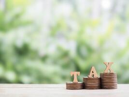 Wooden blocks with the word TAX on stack of coins. The concept of saving money for payment tax in future photo