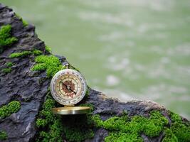 Compass on the rock with green moss background. The concept of world tourism day, Searching the right directions and Travel photo