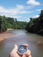 Close up of compass in woman hand with nature as background. The concept of world tourism day, Searching the right directions and Travel photo