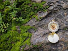 Compass on the rock with green moss background. The concept of world tourism day, Searching the right directions and Travel photo