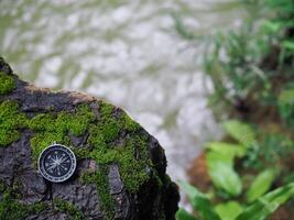 Compass on the rock with green moss background. The concept of world tourism day, Searching the right directions and Travel photo