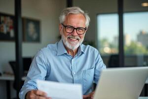 A man with glasses and a beard is smiling while using a laptop photo