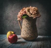 Vase with hydrangea flowers and two apples on the table photo