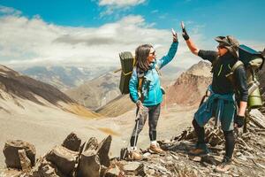 Two caucasian adult hikers together stand hugging caring on top mountain enjoy panorama. Man and woman standing and hugging on the top of the mountain, autumn hike with backpacks.Alpine Kelitsadi lake photo